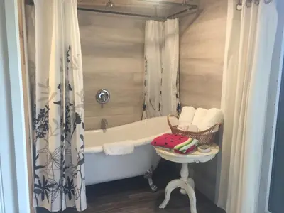 a bathroom with a bath tub and a stool next to a table at The Wood Shed with hot tub in Oyster Bay