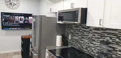 a kitchen with a microwave and a refrigerator and a tv at Executive 1Bedroom Suite By Henday in Edmonton