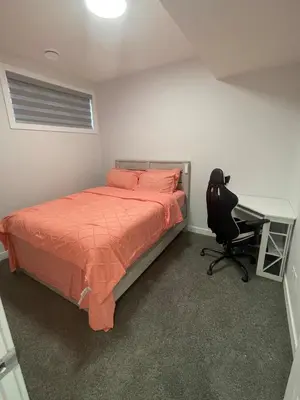 a bedroom with a bed and a desk and a chair at Cozy and modern two bedroom guest suite in Calgary