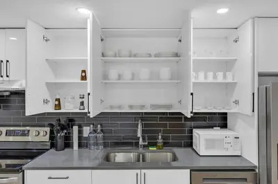 a kitchen with white cabinets and a sink and a microwave at Brand New Private Secondary Suite in Mahogany in Calgary