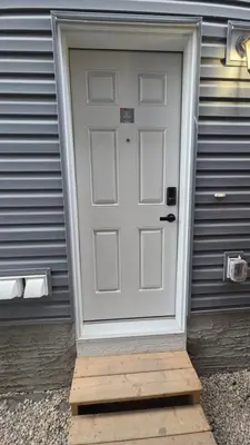 a white door on a house with a wooden doorstep at Modern 2BR Suite in Seton, Calgary in Calgary