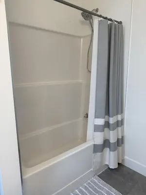 a bathroom with a tub and a shower curtain at Modern 1BR Suite with Laundry, Workspace & WiFi in Langford