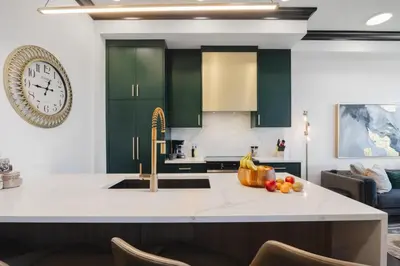 a kitchen with green cabinets and a clock on the wall at Walk University District, Near Hospitals & Shops in Calgary