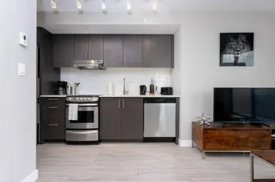 a kitchen with dark brown cabinets and a television at Corporate Stays Hendrix - 2 Bedrooms in Edmonton
