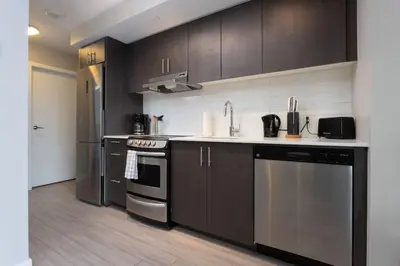a kitchen with stainless steel appliances and brown cabinets at Corporate Stays Hendrix - 2 Bedrooms in Edmonton