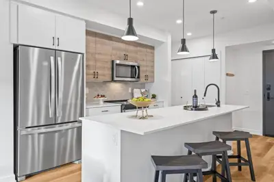 a kitchen with a stainless steel refrigerator and stools at 3BR Mountain Bliss Retreat with Gym Hot Tub and Sauna in Canmore
