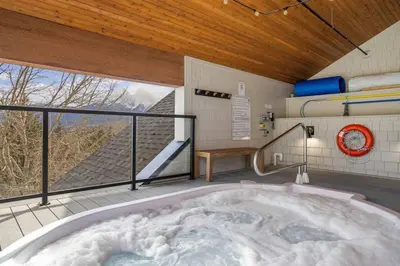 a large bath tub in a room with a window at 3BR Mountain Bliss Retreat with Gym Hot Tub and Sauna in Canmore