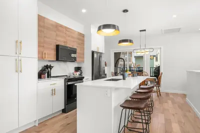 a kitchen with white cabinets and a bar with stools at Modern 4BR Mountain Retreat Balcony BBQ near DT in Canmore