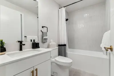 a white bathroom with a sink and a toilet and a tub at 4BR Golden Ridge Mountain Escape with Hot Tub and Gym in Canmore