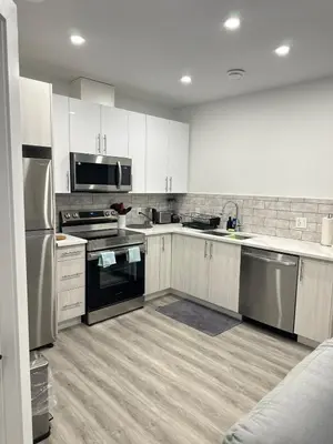 a kitchen with white cabinets and stainless steel appliances at Modern Basement Suite near West Edmonton Mall in Edmonton