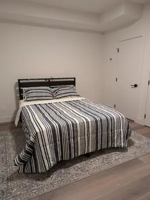 a bedroom with a bed with a striped comforter at 21 Greenwich Common NW Calgary Alberta in Calgary
