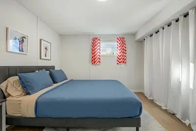 a bedroom with a blue bed and two windows at Family Friendly Welcoming Basement Suite in Calgary