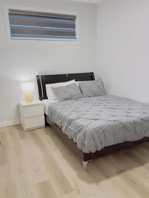 a bedroom with a bed and a night stand at Modern Comfort West Edmonton in Edmonton