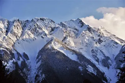 a snow covered mountain range with clouds in the sky at Pemberton Tree Lodge in Pemberton