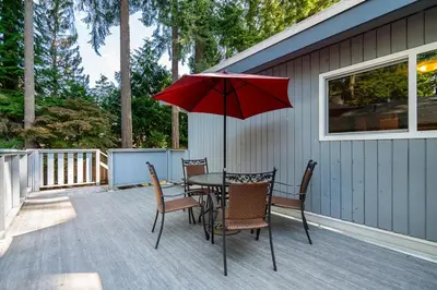 a table and chairs with a red umbrella on a deck at Serene Nature Retreat in North Vancouver