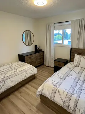 a bedroom with a bed and a mirror and a window at Camelia Home in Kelowna