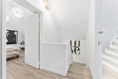 a white hallway with a sliding door leading to a bedroom at Heritage Home in Heart of City with free Parking in Vancouver