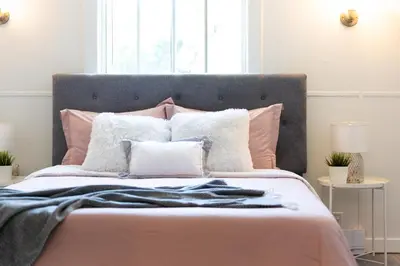 a bed with pink and white pillows and a window at Heritage Home in Heart of City with free Parking in Vancouver