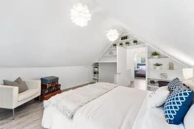 a white bedroom with a white bed and a staircase at Heritage Home in Heart of City with free Parking in Vancouver