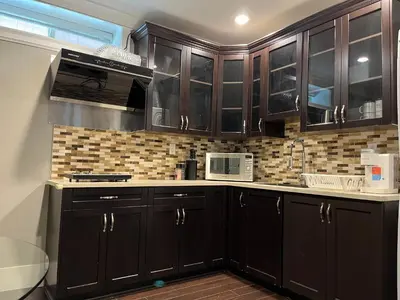 a kitchen with black cabinets and a microwave at Bright New 2BR Suite Near YVR in Vancouver