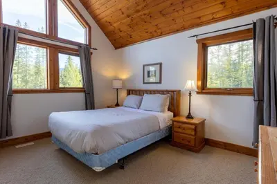 a bedroom with a bed and two windows at Black Diamond Chalet by Fernie Central Reservations in Fernie
