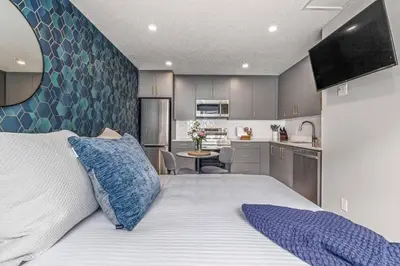 a bedroom with a large bed and a kitchen at Chick and Cozy Haven near Banff with Hot tub and Pool in Canmore
