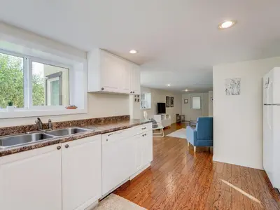 a kitchen with white cabinets and a sink at Gallery Garden - stylish, art-filled 1-bedroom suite by Victoria Prime! in Victoria