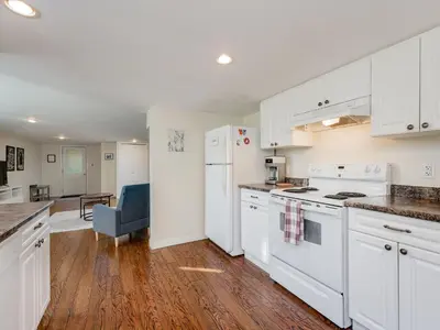 a kitchen with white appliances and a living room at Gallery Garden - stylish, art-filled 1-bedroom suite by Victoria Prime! in Victoria