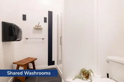 a bathroom with a toilet and a tv and a stool at The Guesthouse Vancouver Downtown in Vancouver