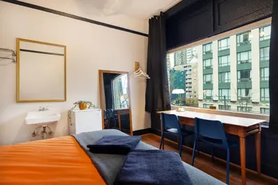 a bedroom with a bed and a desk and a window at The Guesthouse Vancouver Downtown in Vancouver