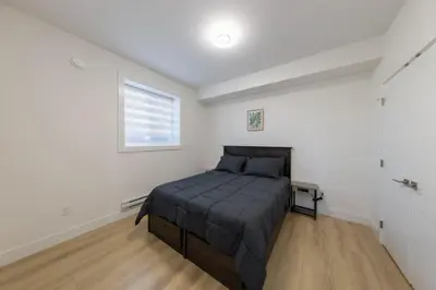 a bedroom with a bed in a white room at Tranquil 2-Bedroom Basement Suite Relaxing Stay in Chilliwack