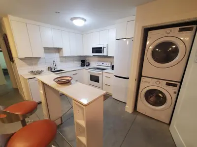 a kitchen with white cabinets and a washer and dryer at Forest Hills in North Vancouver