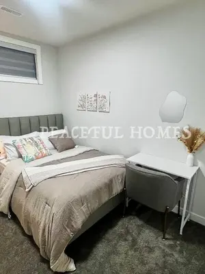 a bedroom with a bed and a desk at Peaceful Homes - Elegant 2 Bedroom Suite in Calgary