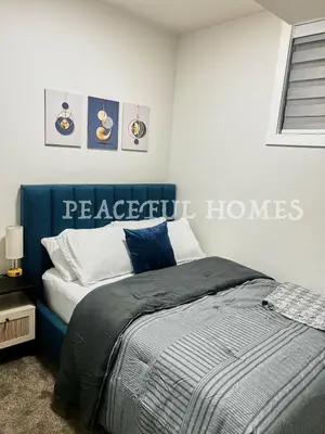 a bedroom with a bed with a blue head board at Peaceful Homes - Elegant 2 Bedroom Suite in Calgary