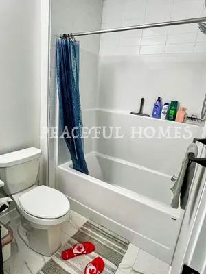a bathroom with a toilet and a bath tub at Peaceful Homes - Elegant 2 Bedroom Suite in Calgary