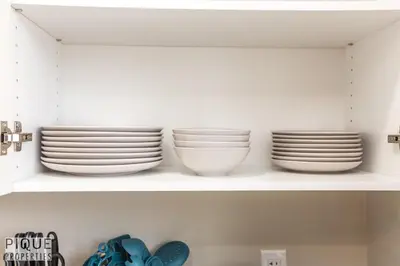 a shelf with plates and bowls on it at Dual-Suite Getaway - Sleeps 12 - Whyte Ave - NFLX in Edmonton