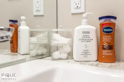 a sink with two bottles of lotion and a mirror at Dual-Suite Getaway - Sleeps 12 - Whyte Ave - NFLX in Edmonton