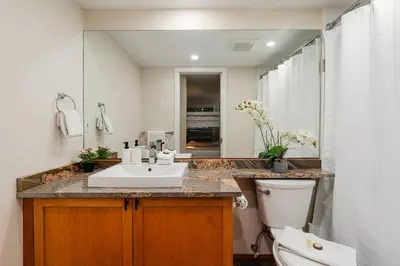 a bathroom with a sink and a toilet and a mirror at Private Hot Tub | Free Parking | Pool | Sauna in Whistler