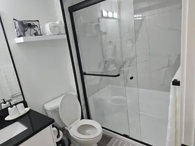 a bathroom with a toilet and a glass shower at L&D Luxury Suite in Nisku