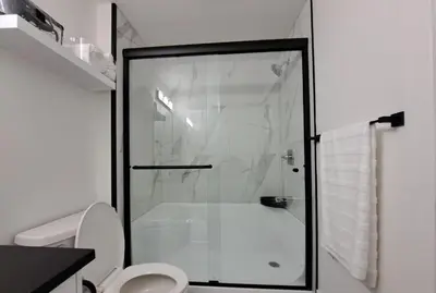 a white bathroom with a shower and a toilet at L&D Luxury Suite in Nisku