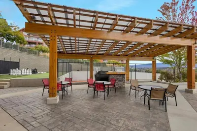 a wooden pergola with tables and chairs and a grill at Lakeview Retreat in West Kelowna in West Kelowna