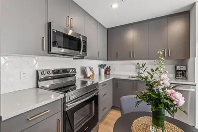 a kitchen with stainless steel appliances and a table with a vase of flowers at Rockies Escape for Groups with Hot tub and Pool in Canmore