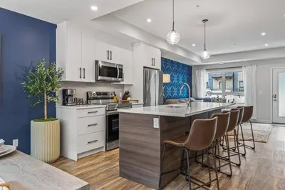 a kitchen with white cabinets and a island with bar stools at Rockies Escape for Groups with Hot tub and Pool in Canmore