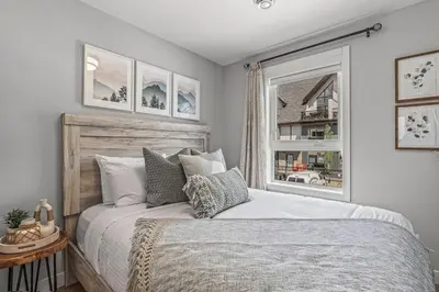 a bedroom with a large bed and a window at New 3BR with Mountain Views Near DT Hot Tub and Pool in Canmore