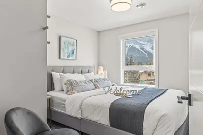 a bedroom with a bed and a chair and a window at 3BR with Stunning Views Self Check-In and Free Parking in Canmore