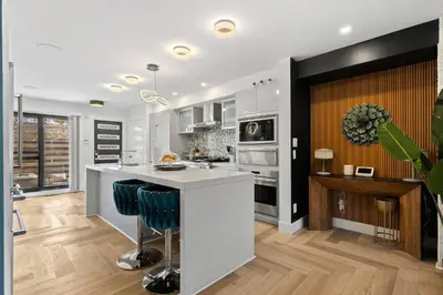 a kitchen with white cabinets and a counter with blue bar stools at *One of a Kind* | Hot Tub| Air Hockey| Pool and… in Calgary