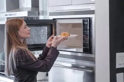 a woman holding a plate of food in a microwave at *One of a Kind* | Hot Tub| Air Hockey| Pool and… in Calgary