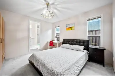 a bedroom with a bed and a desk and two windows at Bright Maple Suite in Richmond