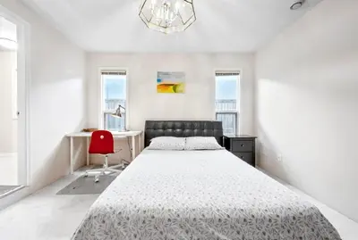 a white bedroom with a bed and a red chair at Bright Maple Suite in Richmond