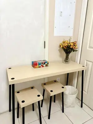a table with two stools and a vase of flowers at Bright Maple Suite in Richmond